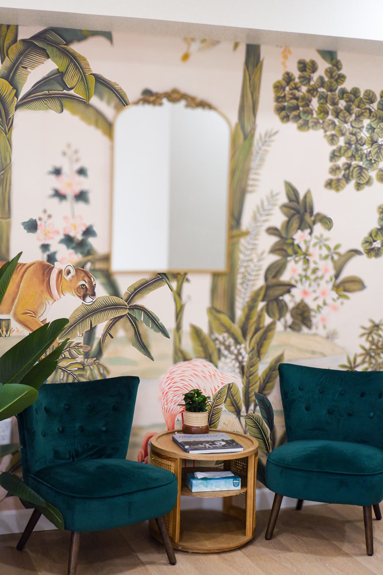 Emerald velvet chairs before a hand-painted mural